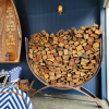 Steel U-shaped firewood storage log rack filled with chopped fire wood.