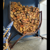 Steel U-shaped firewood storage log rack filled with chopped fire wood.